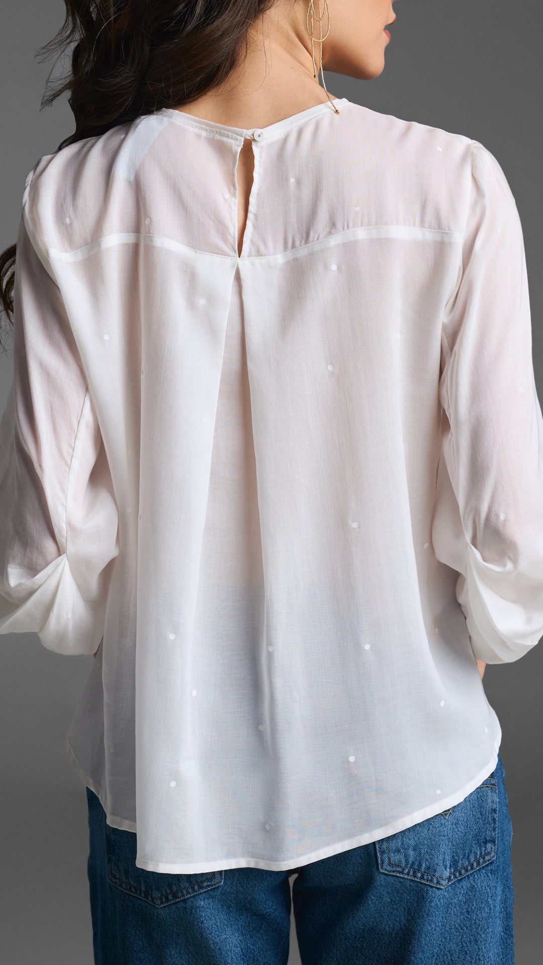 Detalle del drapeado elegante en la manga de blusa blanca fresca 