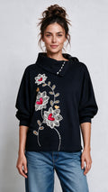 Vista frontal del Buzo Floresta en color negro con manga murciélago y diseño floral estampado.