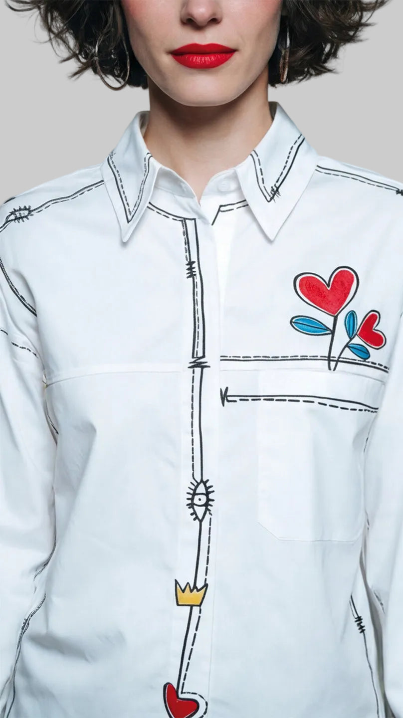 Camisa HILO, esta pieza destaca por sus líneas gráficas negras que simulan costuras e hilos sueltos, enmarcando la prenda con un aire urbano y atemporal.