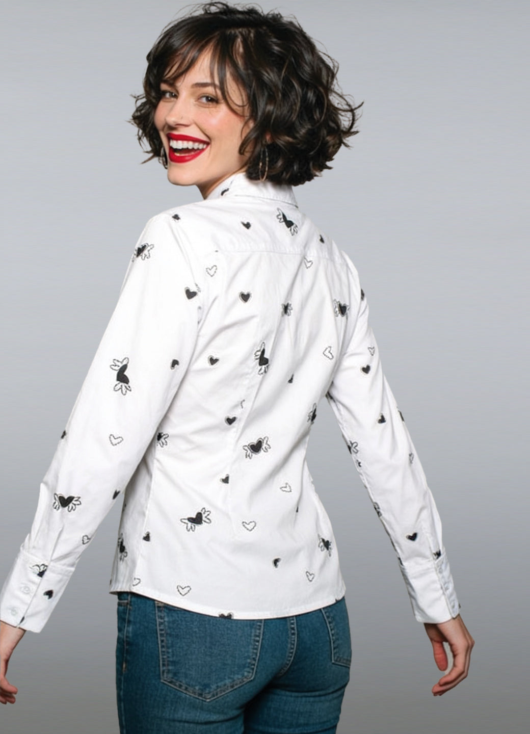 Camisa de manga larga en popelina de algodón blanco. Un diseño que combina comodidad y vanguardia gracias a su estampado de micro-corazones negros y su distintivo aplique rojo en el cuello.