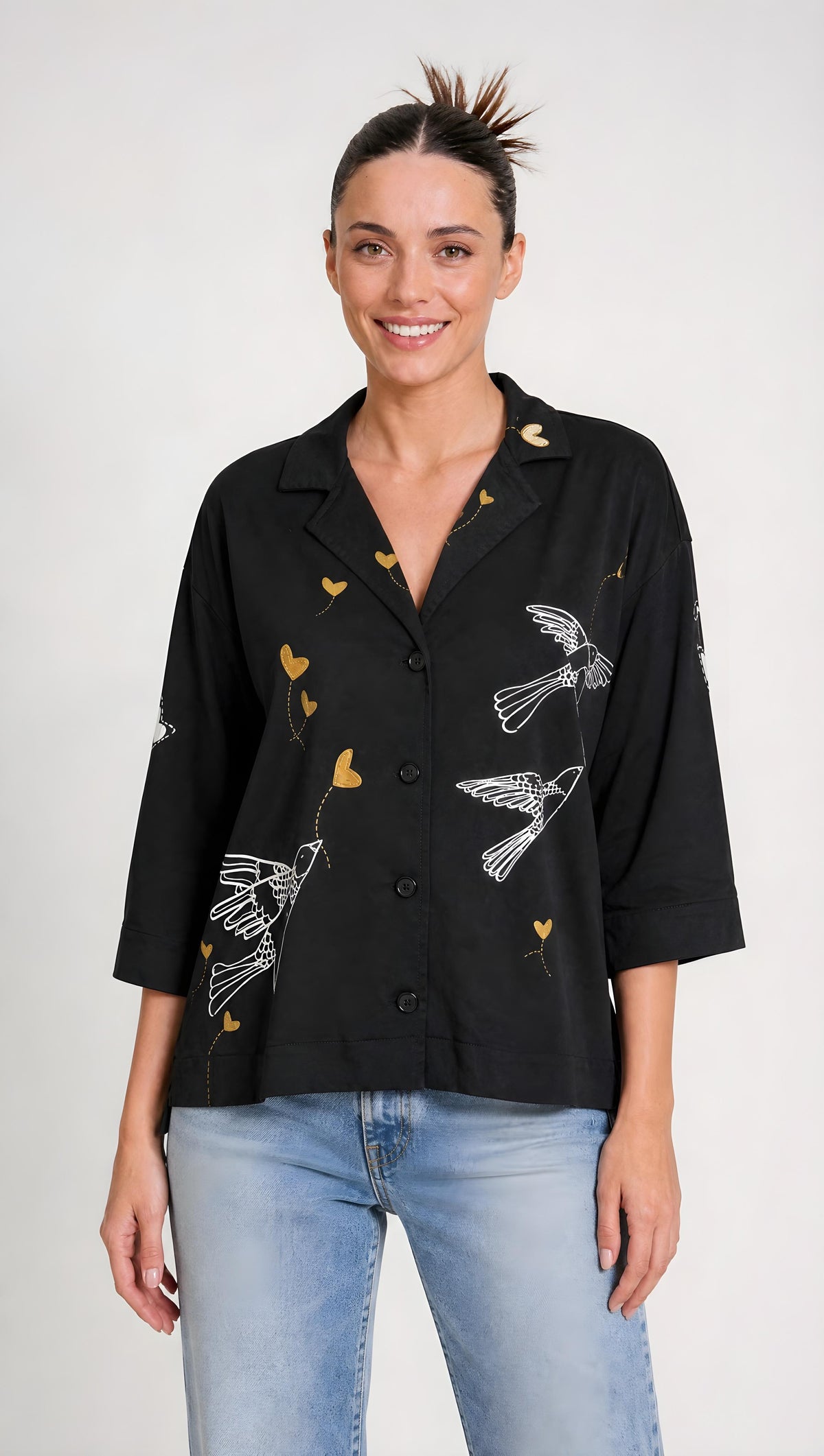 Cuello camisero estructurado con botonadura frontal y trazos ilustrados que destacan sobre el fondo negro profundo.